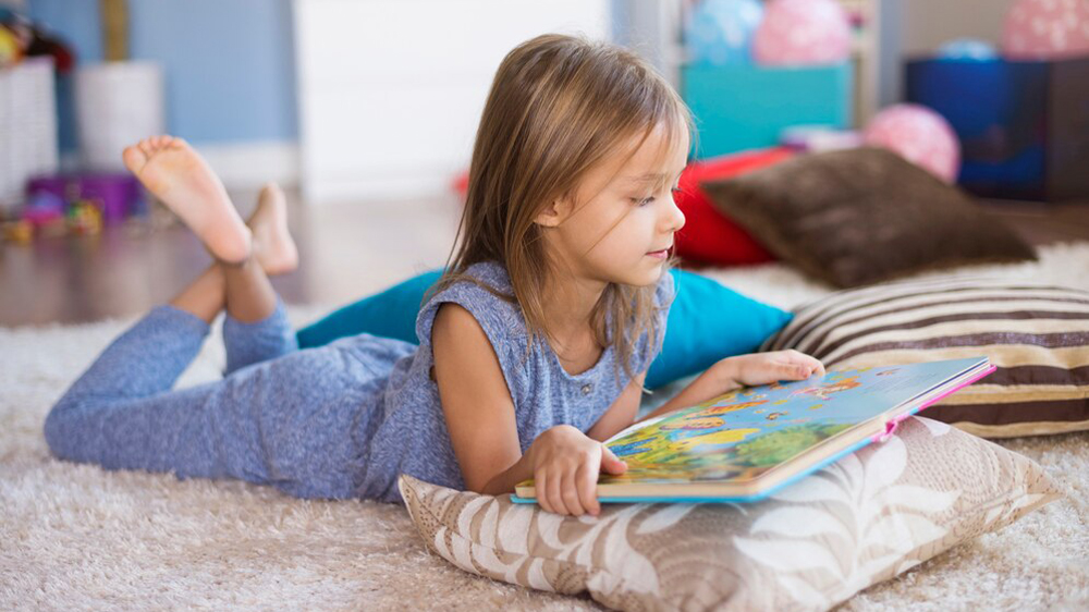 دختربچه‌ای در حال خواندن کتاب داستان