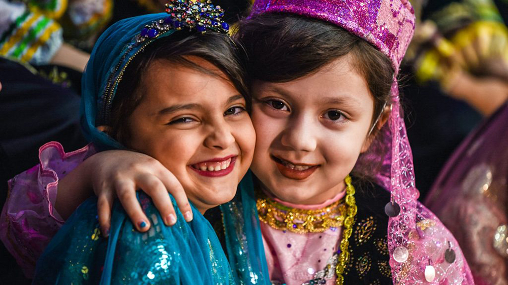 دو کودک دختر در حالی که لباس محلی پوشیدند، لبخند میزنند