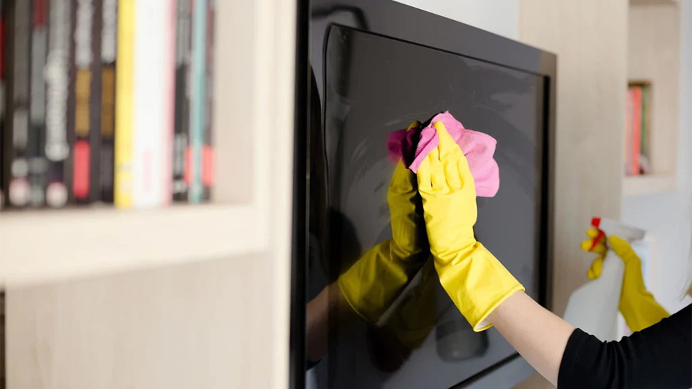تمیز کردن تلویزیون با دستمالی صورتی و دستکش زرد