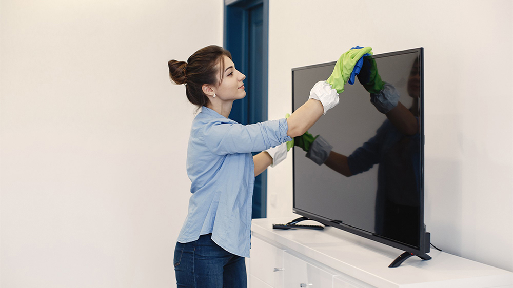 زنی با لباس آبی در حال تمیز کردن تلویزیون