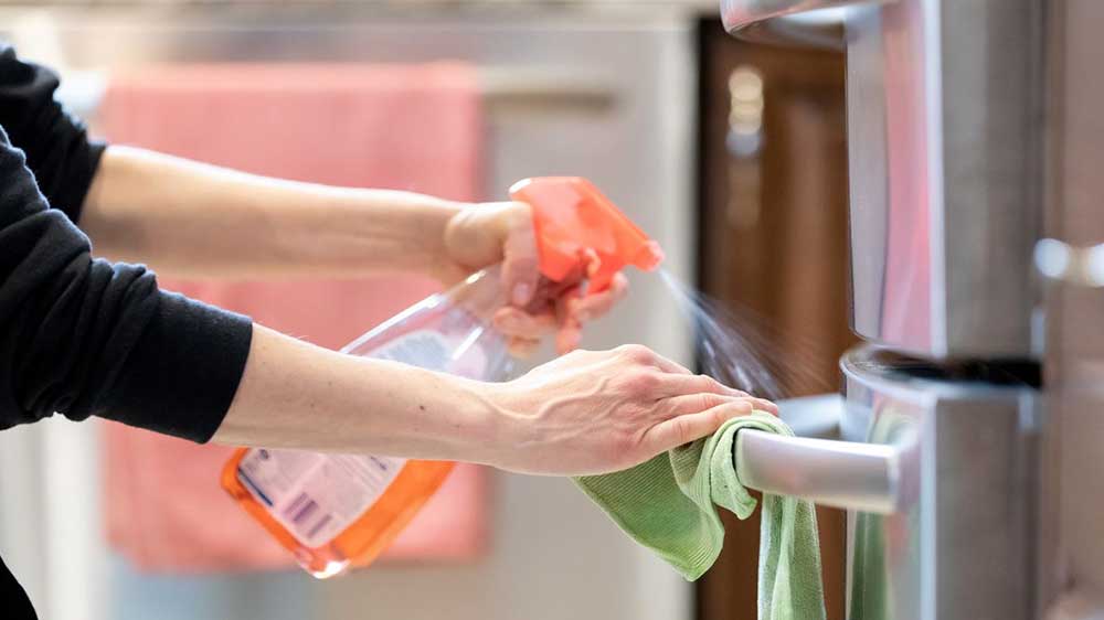 تمیز کردن بدنه و دستگیره‌های خارجی یخچال با استفاده از یک دستمال و اسپری تمیزکننده