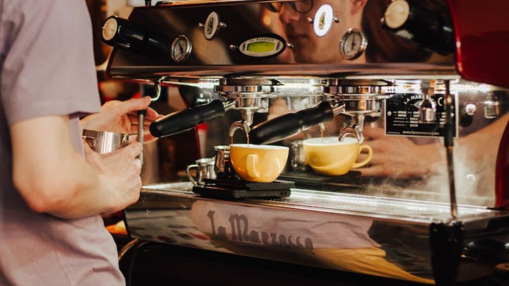 یک مرد در حال تهیه قهوه با دستگاه اسپرسو ساز صنعتی