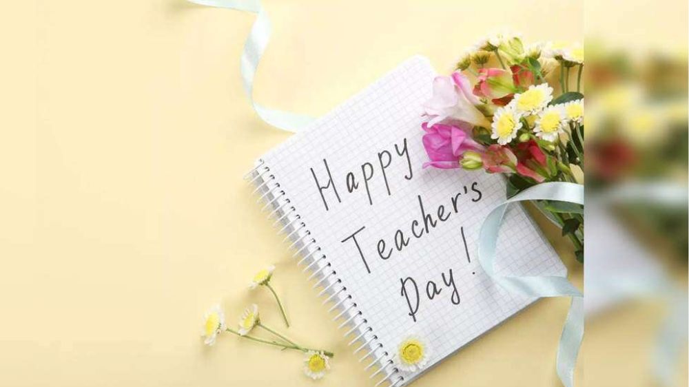 یک دفترچه یادداشت که روی آن به زبان انگلیسی نوشته روز معلم مبارک