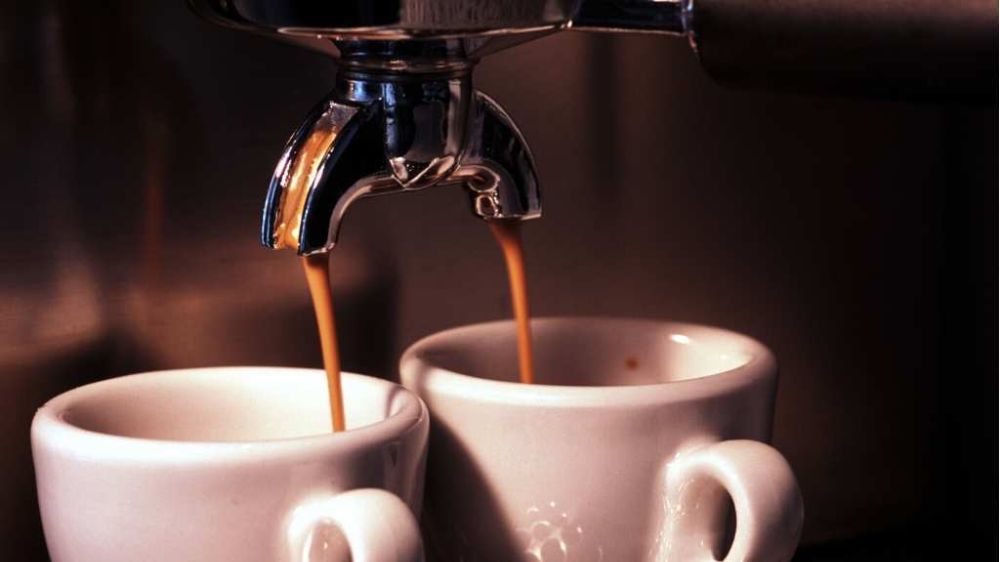 یک کرمای قهوه عالی در حال ریختن در دو فنجان قهوه اسپرسو