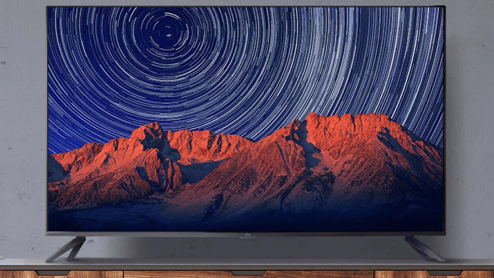 تلویزیون تی سی ال با تصویری از کوه‌ها روی میز چوبی