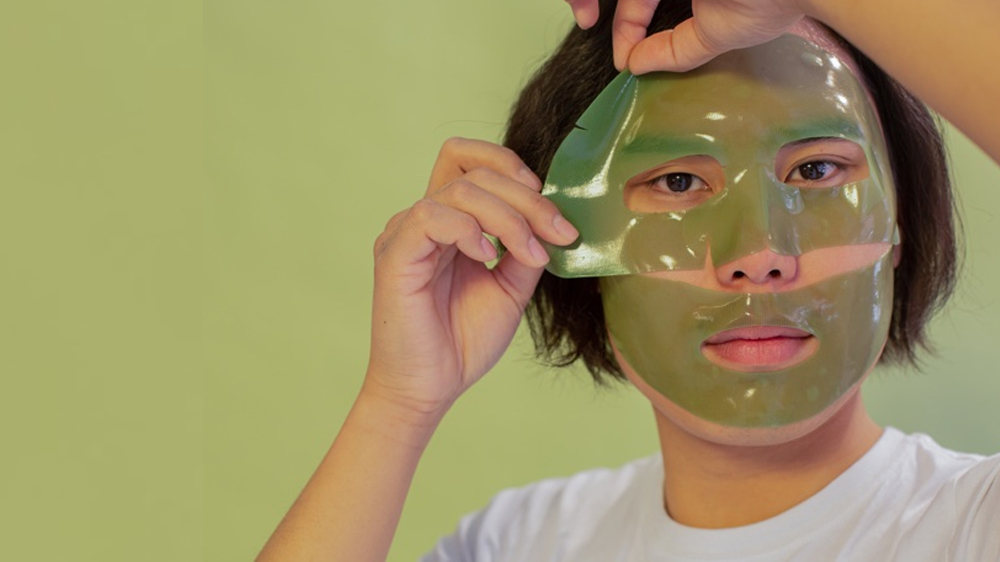یک نوجوان در حال زدن ماسک ورقه ای سبز رنگ