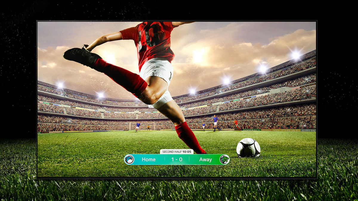 یک تلویزیون در حال پخش یک مسابقه فوتبال و یک بازیکن در حال ضربه زدن به توپ در حالی که خود تلویزیون هم در همان زمین فوتبال قرار گرفته است.