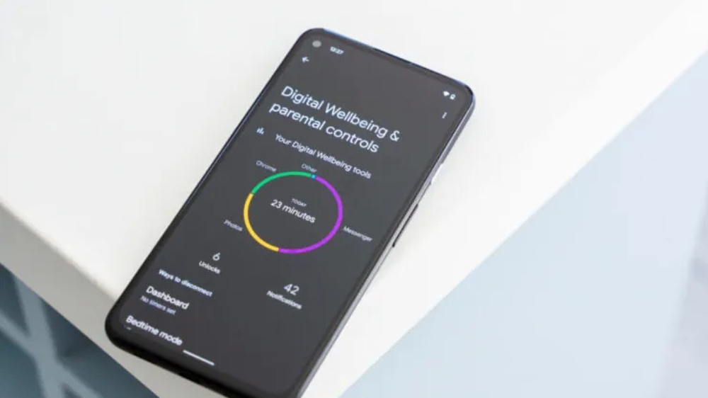یک گوشی موبایل روی یک میز و تنظیمات digital wellbeing روی صفحه آن