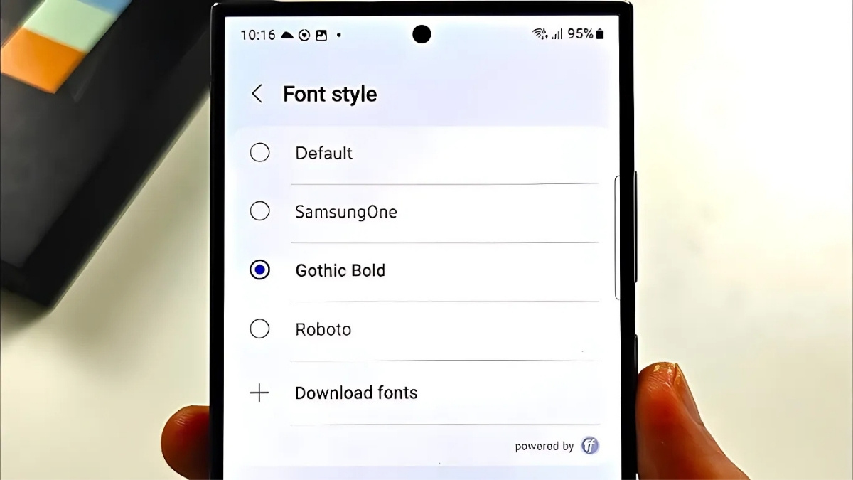 فردی در حال نگه داشتن یک گوشی سامسونگ با تنظیمات تغییر فونت Font style روی صفحه گوشی و انتخاب فونت Gothic Bold