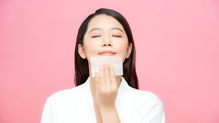یک زن زیبای کره‌ای که چشمانش را بسته است و با یک دستمال در حال پاک کردن صورتش است
