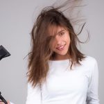 خانمی با موهای بلند و بلوند در حال استفاده از سشوار رمینگتون