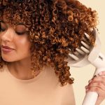 خانمی با موهای فر در حال استفاده از دیفیوزر سشوار