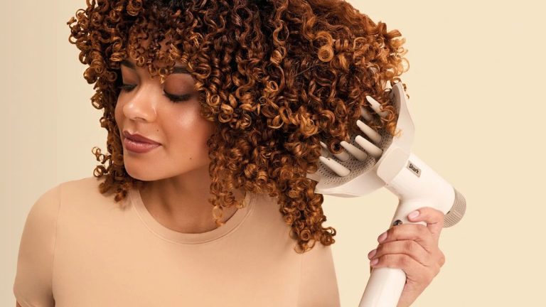 خانمی با موهای فر در حال استفاده از دیفیوزر سشوار