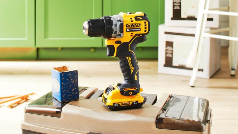 دریل شارژی 12 ولتی dewalt dcd701 روی یک جعبه ابزار در کنار یک جعبه آبی رنگ حاوی پیچ