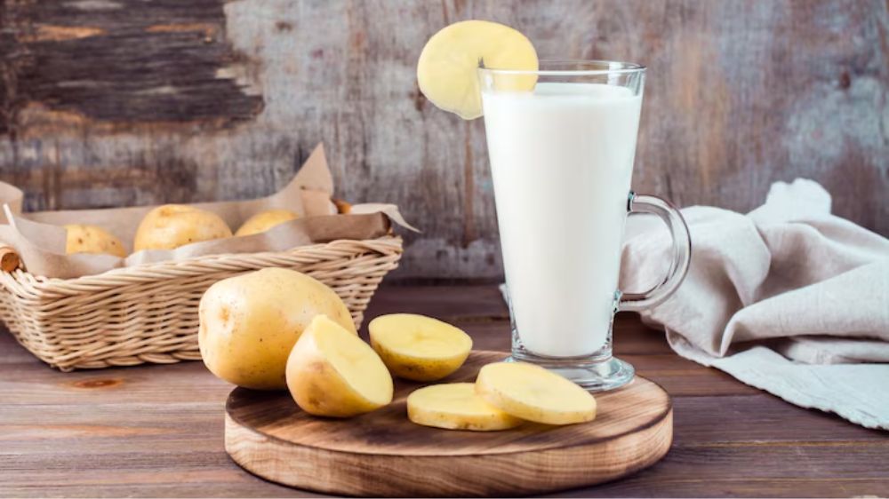 یک لیوان شیر در کنار چند برش سیبزمینی خام چیده شده است.