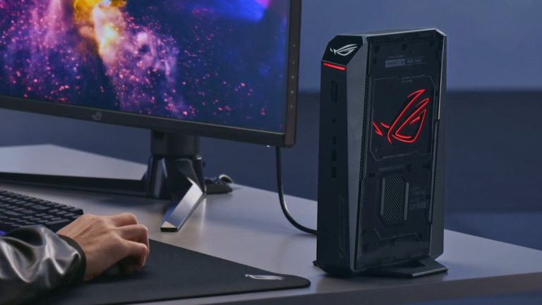 یک نفر در حال کار کردن با مینی کامپیوتر گیمینگ asus rog سری nuc متصل به مانیتور rog با ماوس و کیبورد روی یک میز مرتب