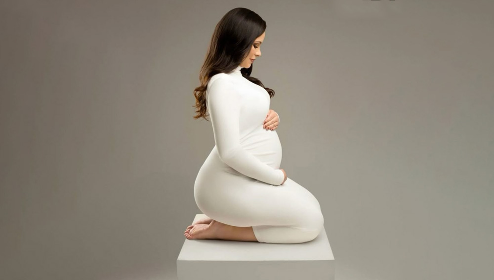 خانم باردار نشسته با پیراهن ساده رنگ سفید