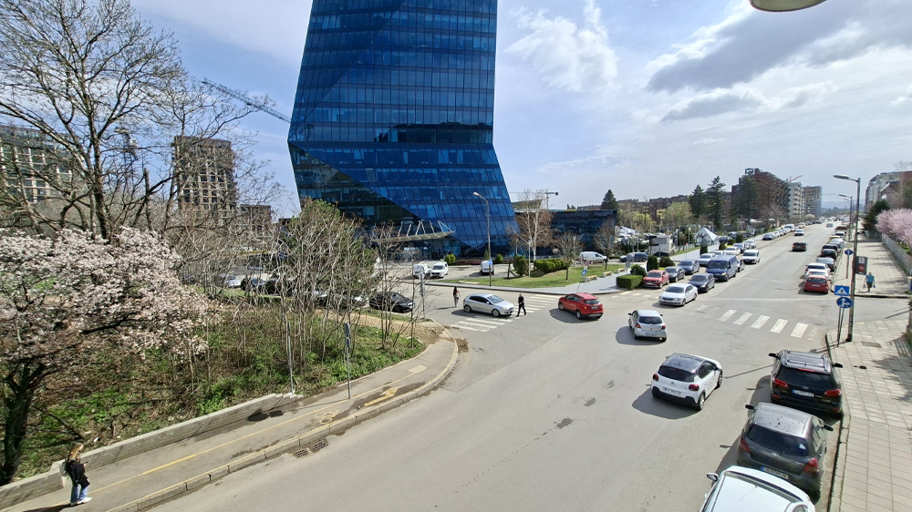 نمونه عکس دوربین اولتراواید گلکسی ای ۵۶ در حال نمایش یک ساختمان آبی رنگ و یک خیابان با ماشین ها