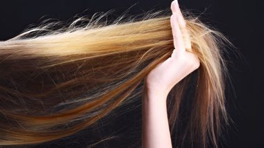 خانمی با موهای بور خود را در دست گرفته است با پس زمینه تیره