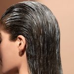 نمای نزدیک از سر خانمی با موهای خیس که به عقب شانه شده و گوشواره‌های حلقه‌ای کوچکی به گوش دارد