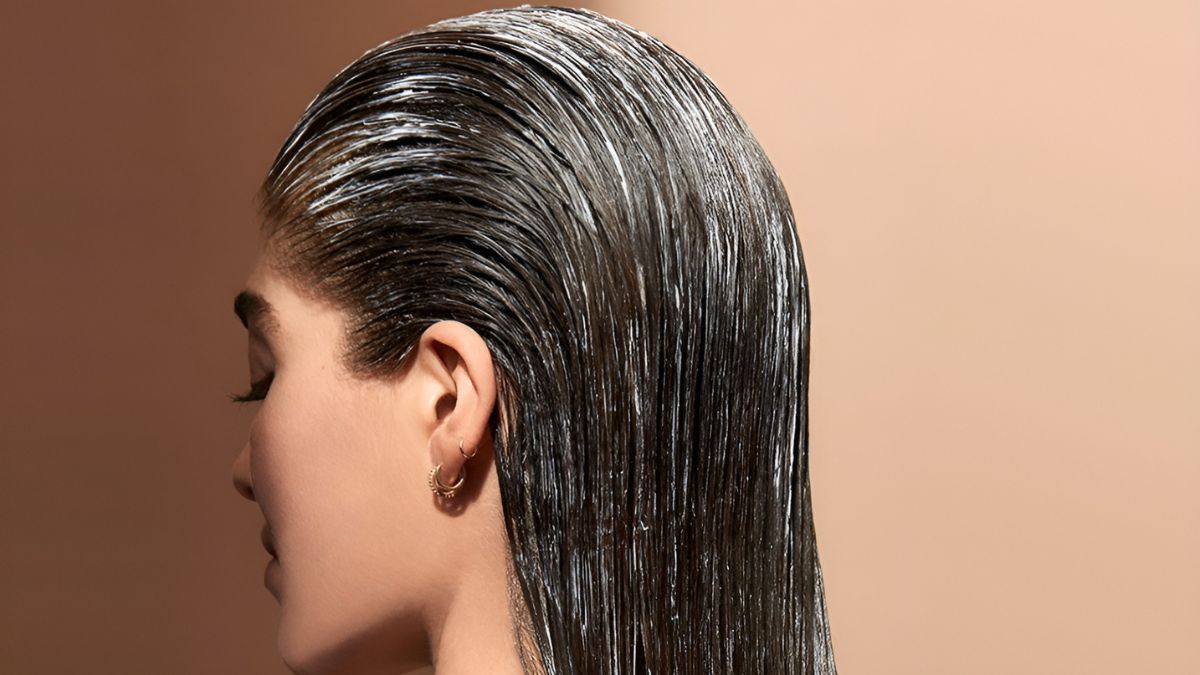 نمای نزدیک از سر خانمی با موهای خیس که به عقب شانه شده و گوشواره‌های حلقه‌ای کوچکی به گوش دارد
