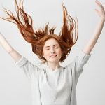 دختر جوان که موهای قرمرش را به سمت بالا پرتاب کرده است.