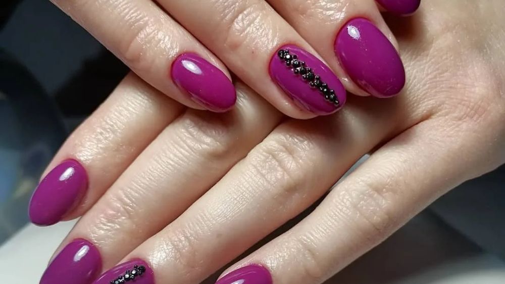 ناخنهایی به رنگ لاک یاسی تیره و تزئين شده با اکسسوری مشکی