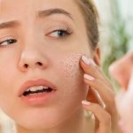 زنی در حال تلاش برای بررسی پوست خشک خود در آینه با نگرانی