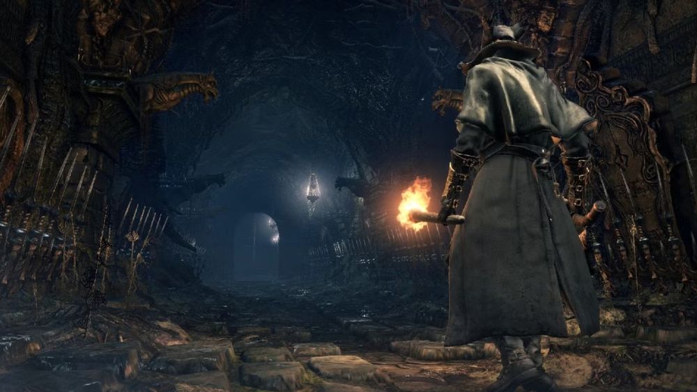 شخصیت The Hunter بازی Bloodborne در حال راه رفتن با یک مشعل در Chalice Dungeon