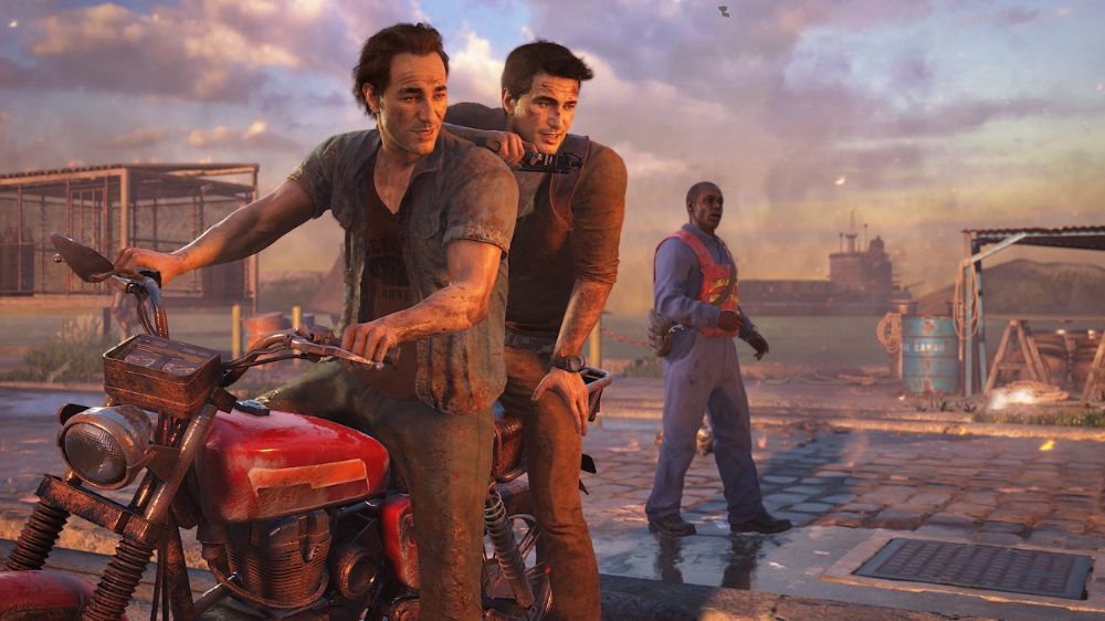 نیتن دریک نشسته پشت سم دریک روی موتورسیکلت در یک بندرگاه در بازی Uncharted 4