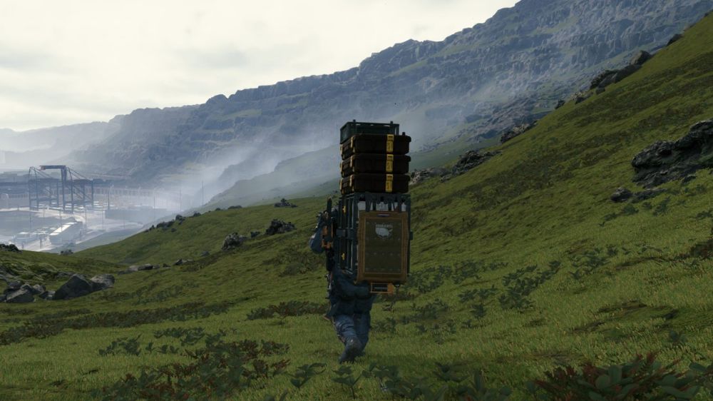 سم پورتر در حال حمل محموله روی دشت سبز در بازی Death Stranding