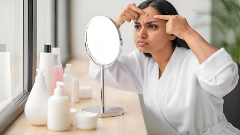 دختر جوان در حال نگاه کردن به جوش صورتش در آینه با چهره درهم