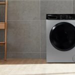 ماشین لباسشویی مدرن دوو در فضایی آرام و مینیمال با دیوار سنگی و کف چوبی