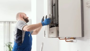 تکنسین با دستکش آبی در حال تعمیر پکیج دیواری سفید در خانه